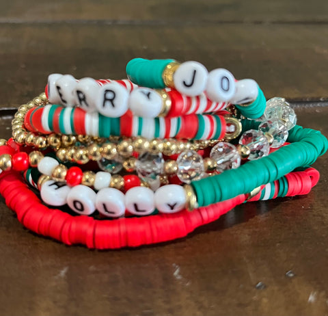 Stack of colorful beaded bracelets with letter beads on a metallic surface